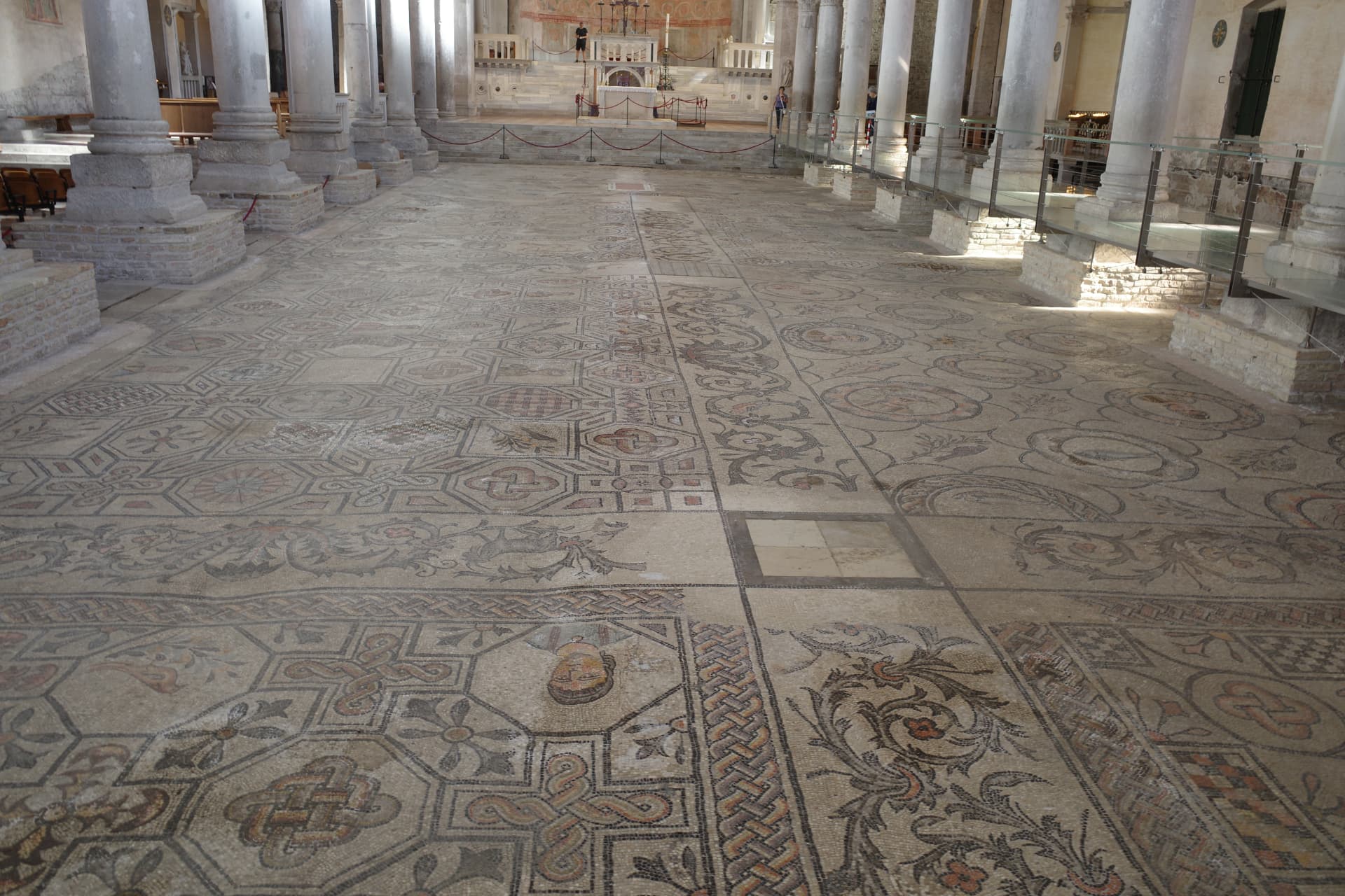 Basilikans golv i Aquileia täckt av mosaiker med flätmönster, rankor och geometriska figurer mellan pelarraderna